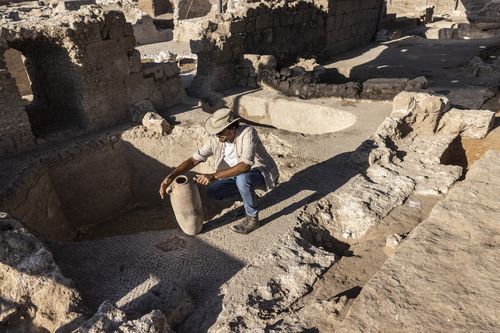 Avshalom Davidesko from the Israel's Antiquities Authority examines a jar in the winemaking complex. (AP Photo/Tsafrir Abayov)