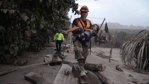 A Guatemalan rescue team worker carries a girl in El Rodeo, Escuintla. (AAP)