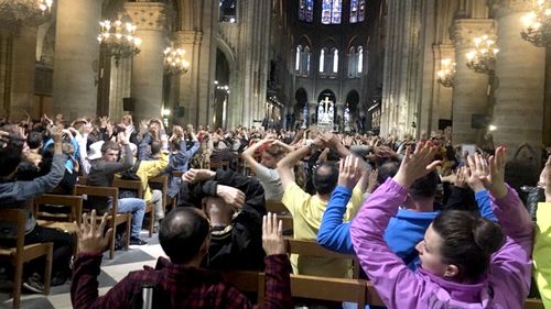 A picture purports to show people with their hands raised inside Notre Dame cathedral after hearing shots fired outside. (Twitter)