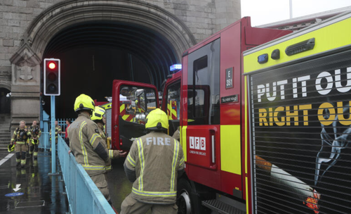 Fire bridge staff speak next to their fire engines parked on Tower Bridge on the River Thames in London, Monday Aug. 9, 2021. London's Tower Bridge was stuck with its roadway arms raised Monday afternoon, snarling traffic on both sides of the River Thames.