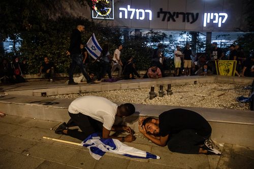 Jewish nationalist demonstrators take cover during a barrage of rockets fired from the Gaza Strip toward central Israel, in the Israeli town of Ramla