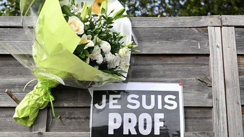 Flowers next to a placard reading "I am a teacher" in tribute to Samuel Paty, the history-geography teacher who was beheaded on October 16, 2020.