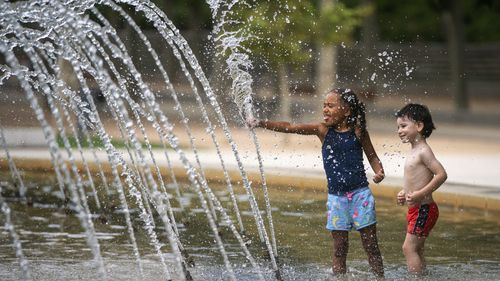 Children cool off in a fountain in a park during a heatwave in Madrid, Spain, Saturday, August 14, 2021. (AP Photo/Andrea Comas)