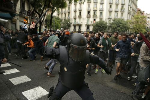 Spanish riot police swings a club against would-be voters near a school assigned to be a polling station by the Catalan government in Barcelona. (AP)