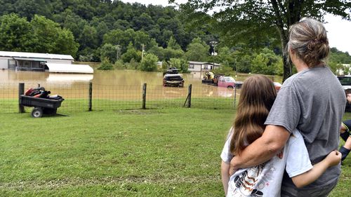 Bonnie Combs, right, hugs her 10-year-old granddaughter Adelynn Bowling watches as her property becomes covered by the North Fork of the Kentucky River in Jackson, Ky., Thursday, July 28, 2022. Flash flooding and mudslides were reported across the mountainous region of eastern Kentucky. (AP Photo/Timothy D. Easley)