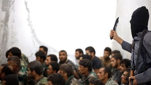 A fighter believed to be from the Islamic State group looks over captured Syrian army soldiers. (AP Photo/Raqqa Media Center of the Islamic State group)