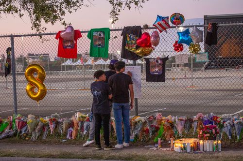 Concert attendees Isaac Hernandez and Matthias Coronel watch Jesus Martinez sign a remembrance board at a makeshift memorial on at the NRG Park in Houston.