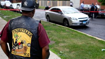 A bystander watches as Chicago Police officers and detectives investigate a shooting where multiple people were shot on Sunday, August 5, 2018 in Chicago, Illinois.