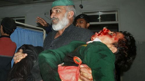 A Pakistani man carries an injured student at a hospital following an attack by Taliban gunmen on a school in Peshawar. (Getty)