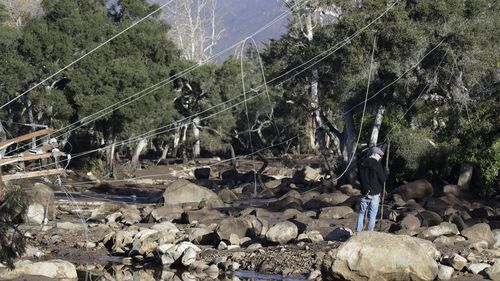 A man stands near downed power lines in Montecito, amid the destruction of a deadly mudslide. (AAP)