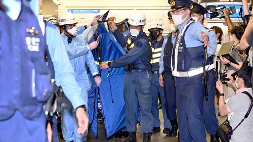 I soccorritori trasportano una barella, che si ritiene stia trasportando un passeggero ferito alla stazione di Sushigaya Okura dopo essere stato accoltellato su un treno dei pendolari, a Tokyo venerdì sera.