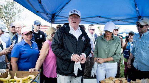 US President Donald Trump and US First Lady Melania Trump put on gloves to had out food while touring the Naples Estates. (AFP)