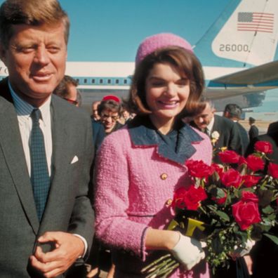 President John F. Kennedy and his wife Jackie, who is holding a bouquet of roses, just after their arrival at the airport for the fateful drive through Dallas.