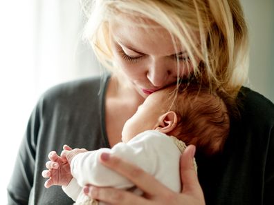 Mum kissing newborn baby