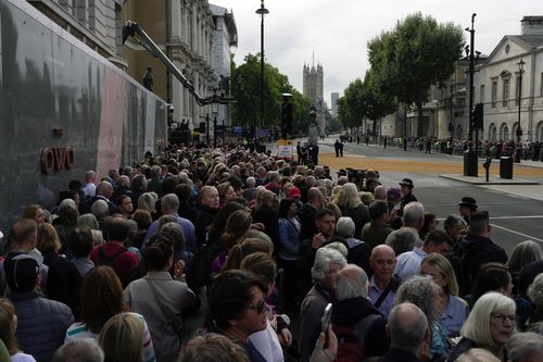 People gather for the procession of Queen Elizabeth II's coffin from Buckingham Palace to Westminster Hall, in London, Wednesday, September 14, 2022. Queen Elizabeth II, Britain's longest-reigning monarch and a rock of stability for most of a turbulent century, has died Thursday 8 September 2022 after 70 years on the throne.  She was 96. (AP Photo/Kin Cheung)