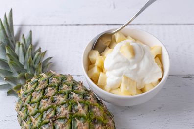 Delicious and healthy fruit snack with fast carbohydrates and protein. Suitable for post workout or pre workout snack or for breakfast and dessert. Chopped pineapple with islandic skyr in a bowl on white background with copy space
