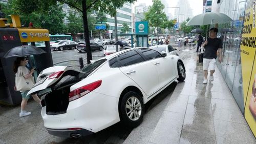 A vehicle is damaged on the sidewalk after floating in heavy rainfall in Seoul, South Korea, Tuesday.