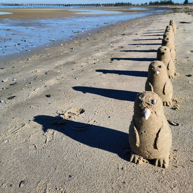 Kel Devoil creates adorable sand penguins along a Melbourne beach