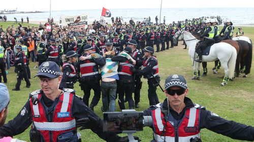 Police on keep protesters apart as a man is arrested on the St Kilda foreshore in Melbourne.