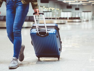 Woman in international airport walking with luggage