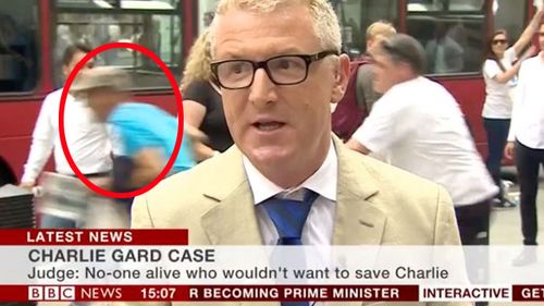 Man dashes past BBC reporter and into path of bus. (BBC)