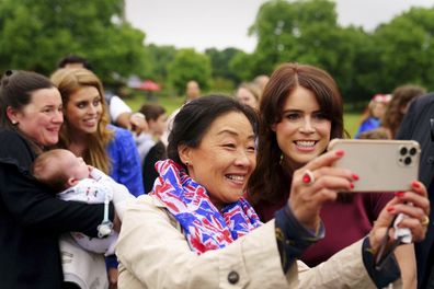 Princess Beatrice, background second from left, and Princess Eugenie have their photographs taken with guests during the Big Jubilee Lunch organised by Westminster Council