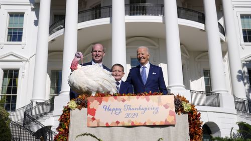 President Joe Biden, right, stands with John Zimmerman, left, chair of the National Turkey Federation, his son Grant Zimmerman, center, and the national Thanksgiving turkey, Peach, during a pardoning ceremony on the South Lawn of the White House in Washington, Monday, Nov. 25, 2024. (AP Photo/Susan Walsh)