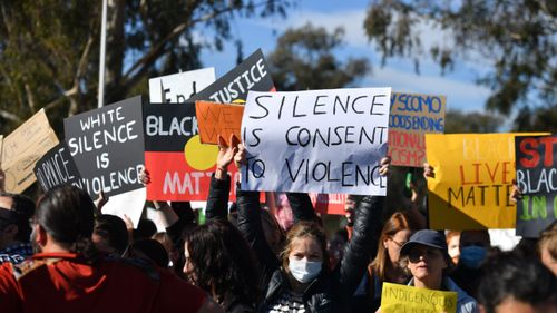 Protesters hold signs in the capital today.