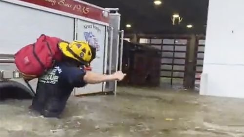This image provided by the Naples Fire Rescue Department shows a firefighter carrying gear in water from the storm surge from Hurricane Ian on Wednesday, Sept. 28, 2022 in Naples, Fla.  