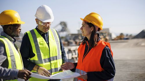 Engineers and architect discussing building plan at construction site