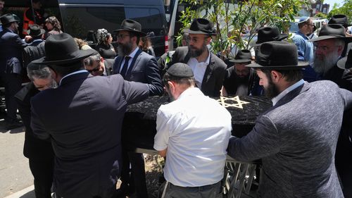 O caixão do Rabino Eli Schlanger, vítima do tiroteio em massa em Bondi Beach, é escoltado para fora de uma sinagoga após seu funeral em Bondi na quarta-feira, 17 de dezembro de 2025, em Sydney, Austrália. (Foto AP / Mark Baker, Piscina)