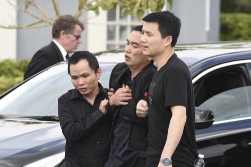 Family members hold up Peter Wang's father, Kong, after the funeral service for his 15-year-old son at Kraeer Funeral Home. (AAP) 