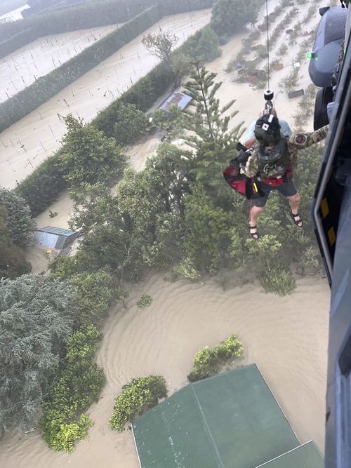 In this image released by the New Zealand Defense Force on Wednesday, Feb. 15, 2023, a person is winched from a rooftop of a home to safety by helicopter in the Esk Valley, near Napier, New Zealand.