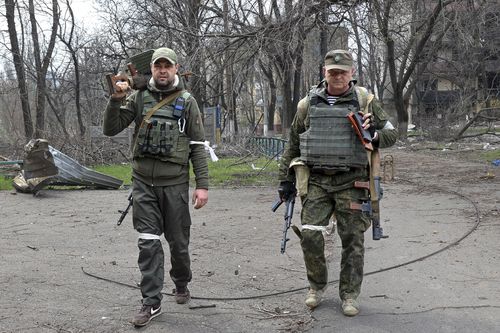 Armed servicemen of Donetsk People's Republic militia look at a photographer as they carry captured weapons in an area controlled by Russian-backed separatist forces in Mariupol, Ukraine, Friday, April 15, 2022. Mariupol, a strategic port on the Sea of Azov, has been besieged by Russian troops and forces from self-proclaimed separatist areas in eastern Ukraine for more than six weeks. (AP Photo/Alexei Alexandrov)