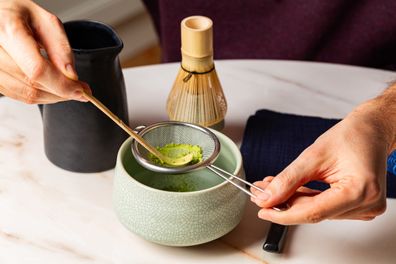Man hands, Cooking green matcha tea during the Japanese ceremony. Traditiobal kit, Bamboo whisk and beverage, spoon shashaku, heated tea bowl known as a chawan. Horizontal image. .