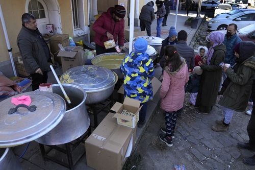 People wait to receive a hot meal, in Iskenderun city, southern Turkey, Tuesday, Feb. 14, 2023. 