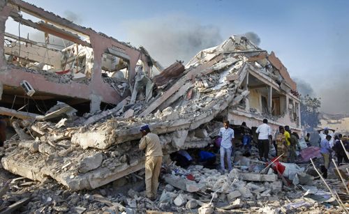 Somalis gather and search for survivors by destroyed buildings at the scene of the blast. (AP)