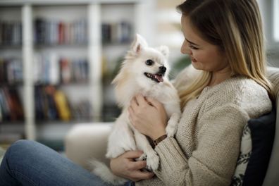 Woman holding her dog as they sit down