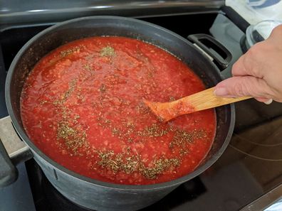 Stirring pasta sauce with a wooden spoon