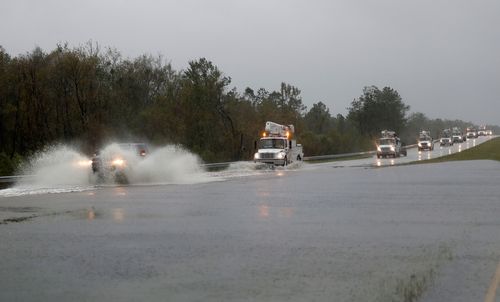 Power company trucks make their way through water on highway US 17 near Jacksonville, North Carolina.