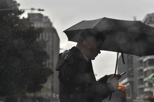 A man is seen crossing the road on a rainy day in Adelaide. (AAP)