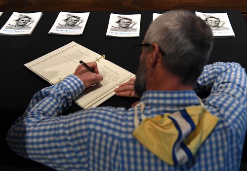 A member of Kurrawa Surf Club signs the condolences book at the memorial service for Dean Mercer on the Gold Coast. (AAP)