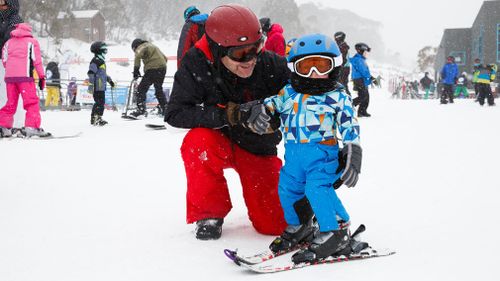 Two-year-old Toby tries skiing as his dad looks on. (Thredbo)