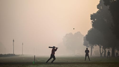 People played cricket at a park in smoky conditions in New Delhi, India.  