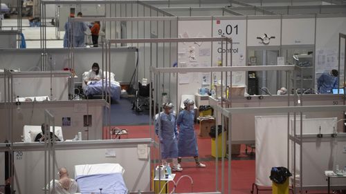 In this April 23, 2020, file photo, doctors walk through a temporary field hospital set at Ifema convention and exhibition of in Madrid, Spain, constructed to treat patients with coronavirus. Spain built at least 16 field hospitals, ranging from a few beds under tents to one with more than 5,000 beds at Madrid's big convention center