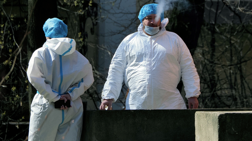 A medical worker wearing protective equipment to protect against coronavirus smokes as he and his colleague rest in the yard of the Pokrovskaya hospital in St.Petersburg, Russia, Monday, May 4, 2020. (AP Photo/Dmitri Lovetsky)
