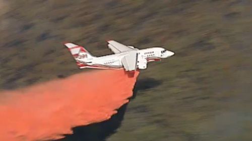 Fixed-wing aircraft are dispersing fire retardant over the blaze.