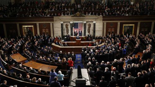 Democrats on the left stay seated while Republicans give a standing ovation to Donald Trump during his State of the Union. (AAP)