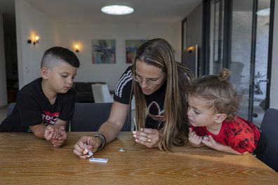 Hila Bohadana drips a solution onto a COVID-19 Antigen Self Test kit after taking a sample from her son, Ori, 10, ahead of the first day of school, at their home in Moshav Kochav Michael near Ashkelon, Israel, Tuesday, Aug. 31, 2021. 