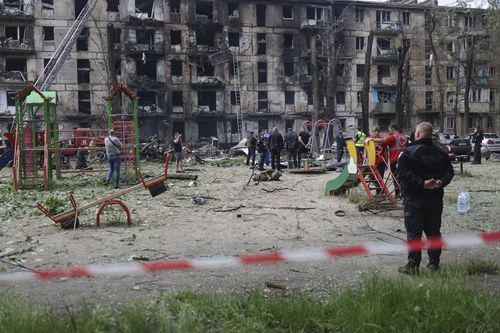 People watch the scene at a damaged multi-storey apartment building caused by the latest rocket Russian attack in Kryvyi Rih, Ukraine, Tuesday, June 13, 2023. 